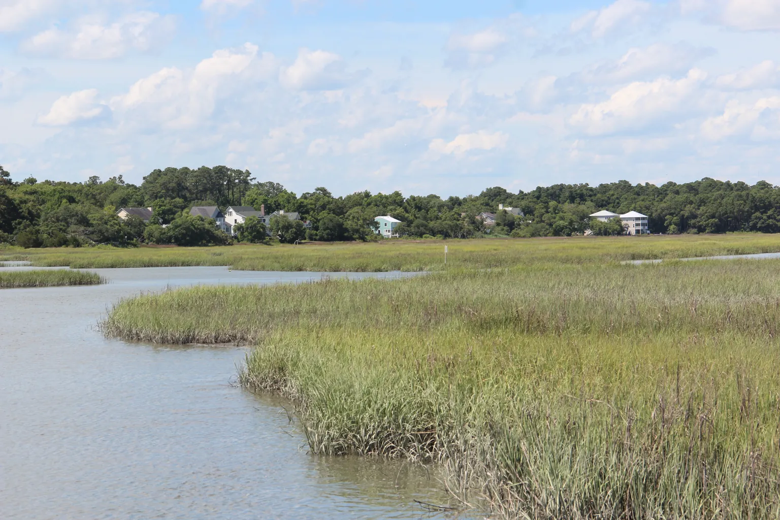 Golden light across a tidal creek, marsh grasses and a distant wooden dock