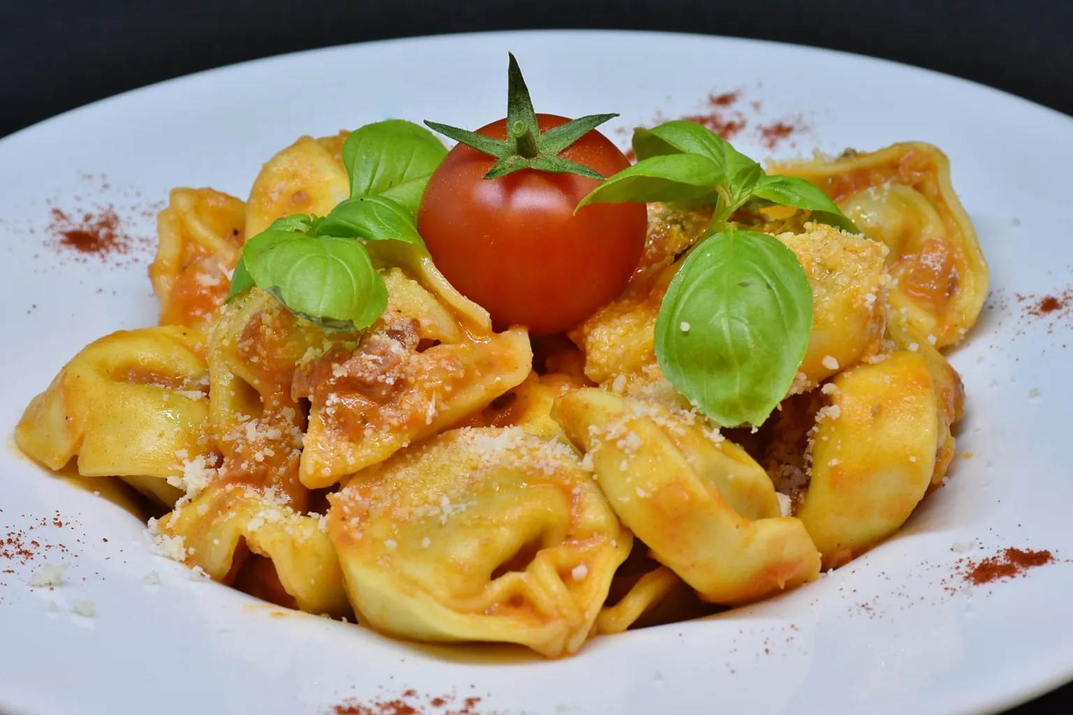A plate of pasta on a linen-covered table with a softly focused waterfront behind it